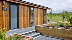 Un chalet moderne avec une façade en bois, une porte noire et une enseigne indiquant « Willow Lodge ».