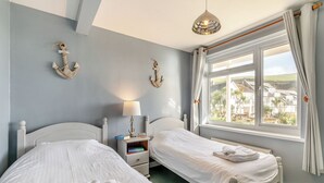 Et soveværelse med to senge, et natbord med en lampe og udsigt ud