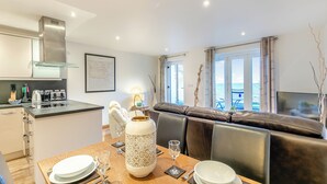 A modern kitchen with a dining area, a large window with a view, and a cozy seating area. - 1 bedroom accommodation in Seaton (Seaton)