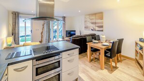 A modern kitchen with a built-in stove, oven, and a large island. - 1 bedroom accommodation in Seaton (Seaton)
