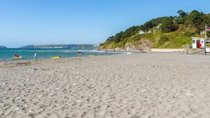 A beach with a lifeguard tower, clear skies, and calm sea. - 1 bedroom accommodation in Seaton (Seaton)