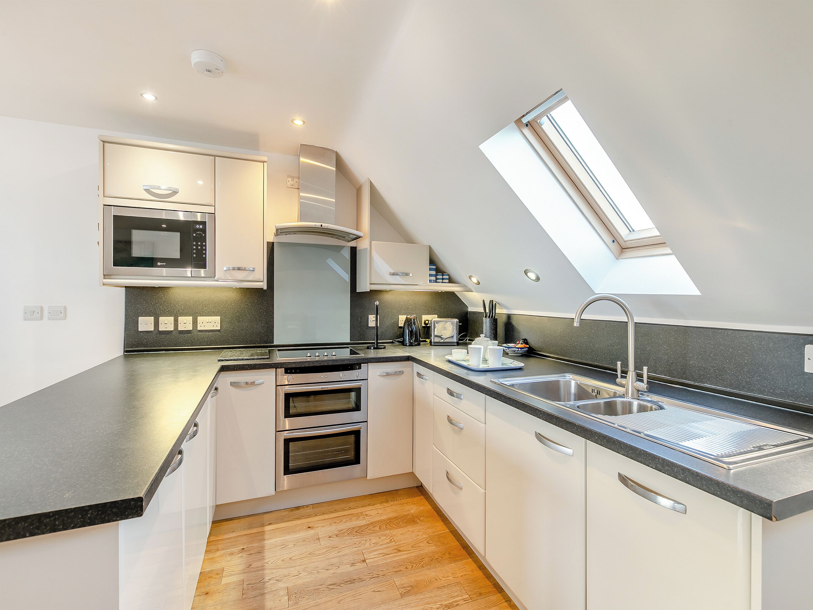 Een moderne keuken met dakraam, inbouwoven en roestvrijstalen apparatuur.