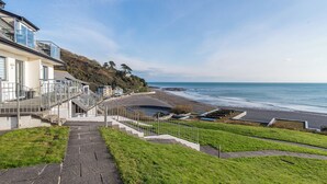 Une propriété située en bord de mer, dotée d’un escalier menant à un balcon avec vue sur la plage.