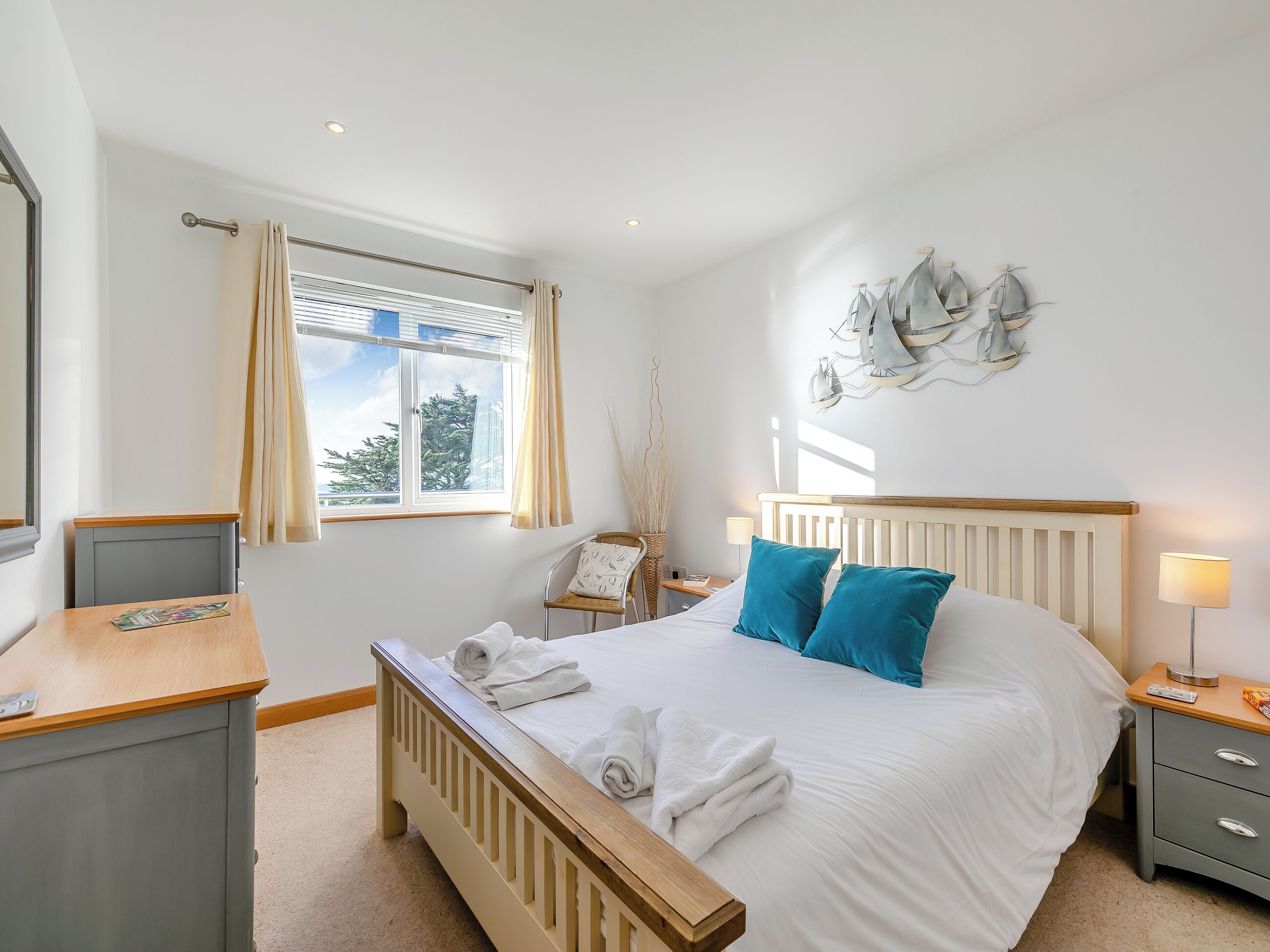 A neatly arranged bedroom with a bed, bedside table, lamp, and a window with curtains.