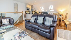 Een moderne woonkamer met een leren bank, een glazen salontafel en een eethoek met houten meubels.
