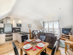 A modern kitchen with a dining area, a sofa, and a TV. - 2 bedroom accommodation in Seaton (Seaton)