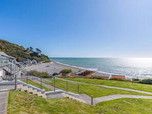 A coastal view with a beach, a staircase leading to a building, and a clear sky. - 2 bedroom accommodation in Seaton (Seaton)