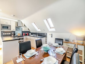 Cocina moderna con comedor, que incluye un tragaluz, electrodomésticos integrados y una mesa de comedor para cuatro.