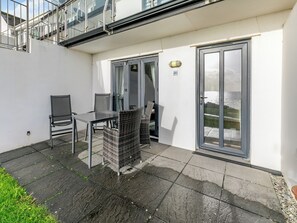A patio area with a table and chairs, a door, and a view of the sea. - 24 Mount Brioni, Nr Looe (Seaton)