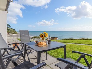 Une terrasse avec une table mise pour le petit-déjeuner, offrant une vue sur la côte.