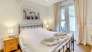 Een slaapkamer met een bed, nachtkastjes, een lamp, een schilderij en uitzicht.