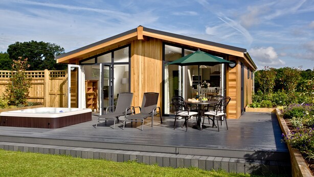 Une maison moderne dotée d’une terrasse, d’un jacuzzi et de mobilier d’extérieur.