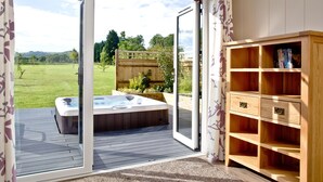 Une pièce dotée d’une porte-fenêtre coulissante donnant sur un patio, un jacuzzi et une bibliothèque en bois.