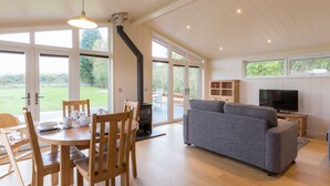 A spacious living area with a dining table, chairs, a sofa, a television, and a fireplace.