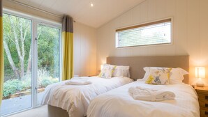 A bedroom with two beds, a sliding glass door, and a window with blinds.