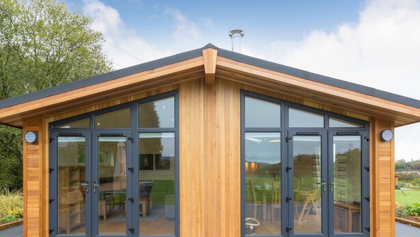 A modern building with a wooden exterior and large glass doors.