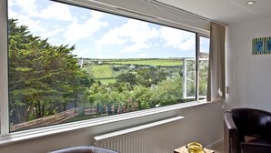 Ein Zimmer mit großem Fenster und Blick auf eine grüne Landschaft und Bäume.