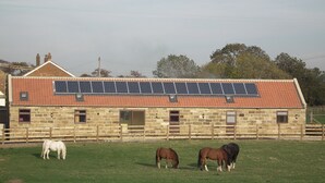 A stone building with a red-tiled roof and solar panels. - Byre Cottages**Nr Stokesley (Carlton near Stokesley)