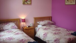A bedroom with two beds, each with floral bedding, a bedside table with a lamp, and a picture on the wall. - Byre Cottages**Nr Stokesley (Carlton near Stokesley)