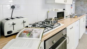 A kitchen with white cabinets, a gas stove, a microwave, and a toaster.