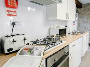 Una cocina con armarios blancos, estufa a gas, microondas y tostadora.