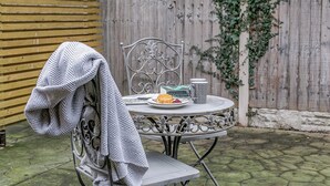 A metal table with a chair, a blanket draped over the chair, and a plate with food and a mug. - Mill Farm Cottages - The Nook (Barlow near Bakewell)