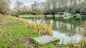 A tranquil lakeside setting with a wooden dock, a small pavilion, and a grassy area.
