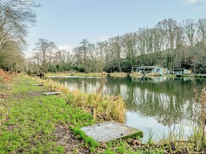 A tranquil lakeside setting with a wooden dock, a small pavilion, and a grassy area.