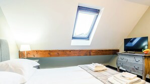 Ett sovrum med en säng, en träram som fungerar som sänggavel, en tv-apparat på en byrå och ett fönster.