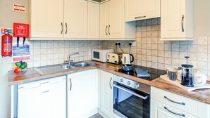Ett kök med vita skåp, en mikrovågsugn, en brödrost, en vattenkokare och en kaffebryggare.