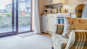 Cucina con mobili bianchi, microonde, fornello e finestra con vista sulla strada.