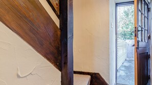 Un corridoio stretto con una scala in legno che conduce a una porta.