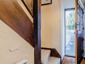 A narrow hallway with a wooden staircase leading to a door. - 4 lovely Cottages situated in the beautiful Derbyshire village of Barlow. (Barlow near Bakewell)