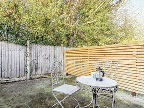A patio with a round metal table and a metal chair, a wooden fence, and a wooden slatted wall. - 4 lovely Cottages situated in the beautiful Derbyshire village of Barlow. (Barlow near Bakewell)