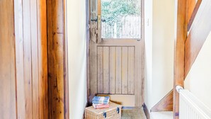 A wooden door with a window, a wicker basket with boxes, and a white radiator. - Mill Farm Cottages - Kingfisher (Barlow near Bakewell)