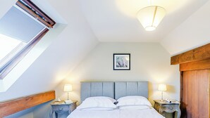 A neatly made bed with white linens and towels, a framed picture on the wall, and a skylight above. - Mill Farm Cottages - Kingfisher (Barlow near Bakewell)