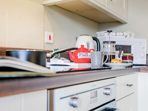 Eine Küche mit Wasserkocher, Kaffeemaschine, Mikrowelle und Toaster.