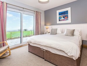 A bedroom with a large bed, a chair, a nightstand, a lamp, and a painting on the wall. - 2 bedroom accommodation in Gatehouse of Fleet (Gatehouse of Fleet)