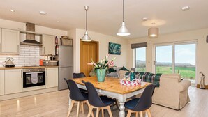 Una cocina moderna con comedor, piso de madera y vistas al campo.