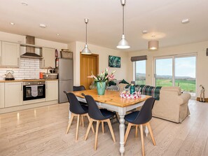 A modern kitchen with a dining area, wooden flooring, and a view of the countryside. - 2 bedroom accommodation in Gatehouse of Fleet (Gatehouse of Fleet)