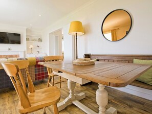 Un comedor con una mesa de madera, sillas, una lámpara y un espejo.