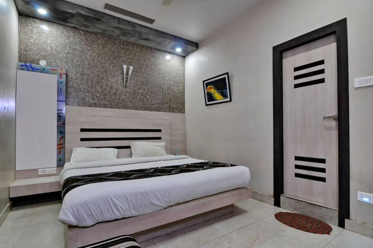 Ein modernes Schlafzimmer mit einem großen Bett, einem Kleiderschrank, einem kleinen Tisch und einer Tür mit einem besonderen Design.
