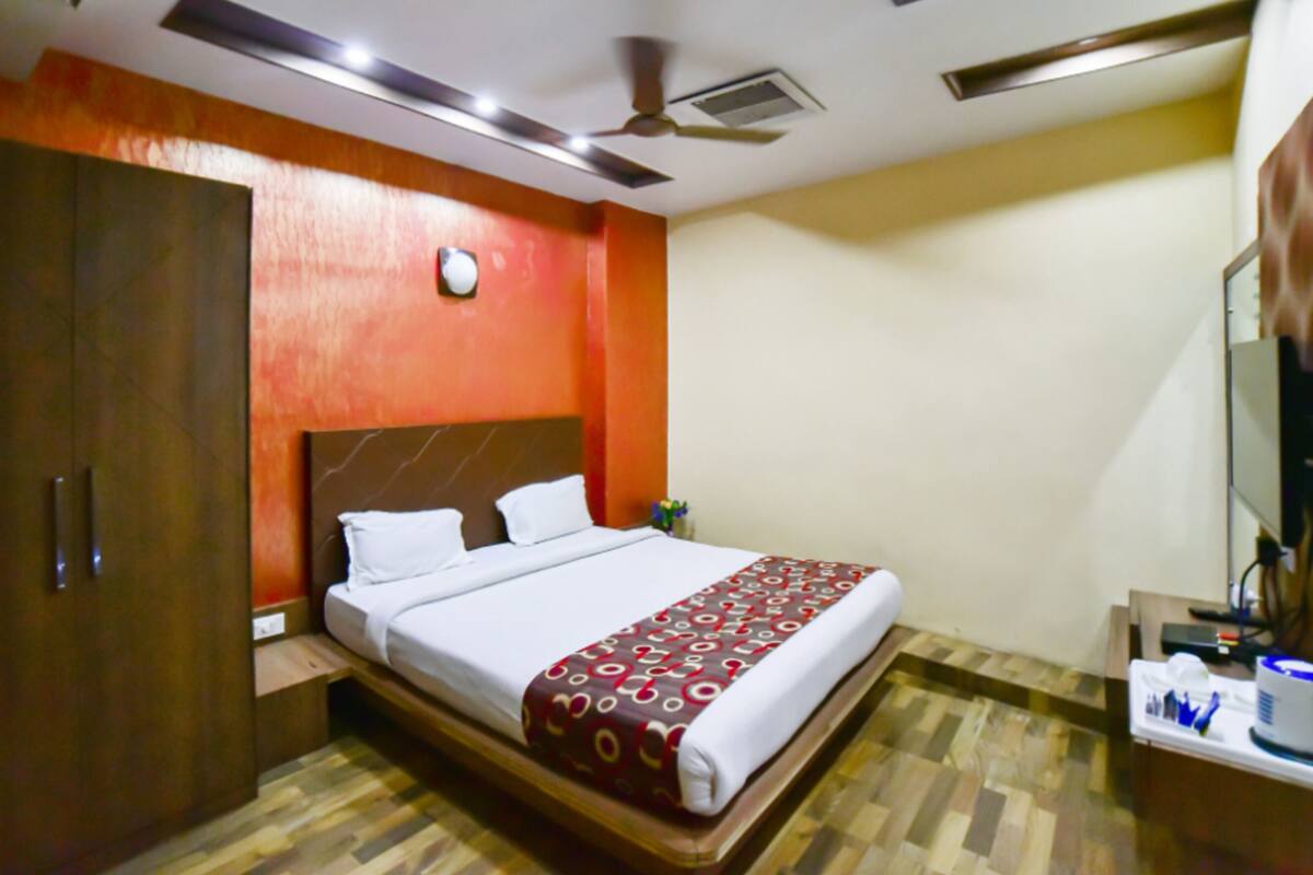 Ein Hotelzimmer mit Bett, Schrank, Schreibtisch mit Spiegel und Deckenventilator.