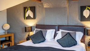 Ein Schlafzimmer mit einem großen Bett, zwei Nachttischen, einem Spiegel und Wandbildern.