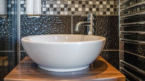 Ein Badezimmer mit einem weißen Waschtisch, einem Chrom-Wasserhahn und einer schwarz-weiß gefliesten Rückwand.