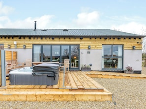 A modern building with a wooden deck, hot tubs, and a large window. - Fairchild's Barn - UK12806 (Caldecott, near Uppingham)