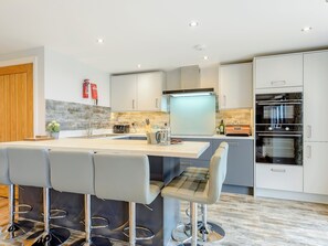 Una cocina moderna con una isla central, taburetes de bar y electrodomésticos integrados.