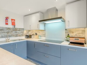 A modern kitchen with a stainless steel range hood, a toaster, and a knife block.