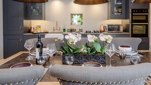 Une cuisine moderne avec des meubles de couleur sombre, un îlot central et des luminaires suspendus.