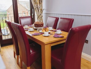 A dining table with six red chairs, a cake, and tea cups. - 3 bedroom accommodation in Castle Carrock, near Brampton (Castle Carrock, near Brampton)